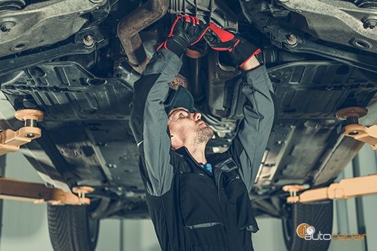 Mechanic performing factory scheduled maintenance under a vehicle