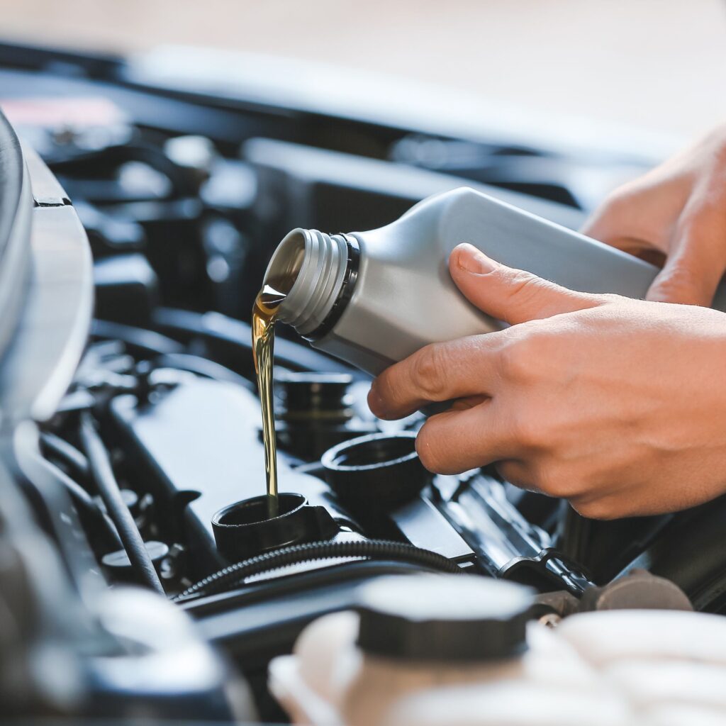 person pouring oil into car engine